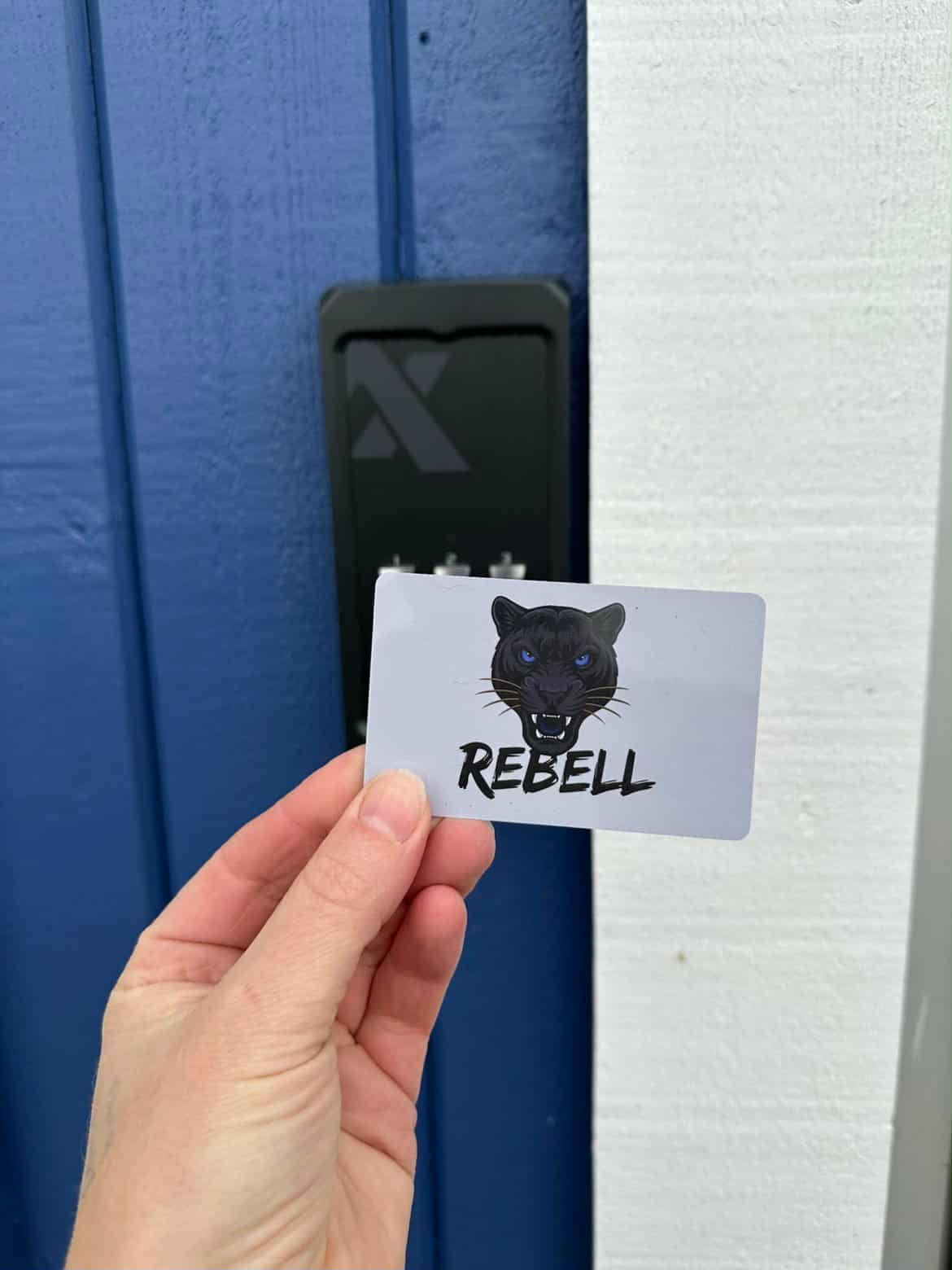 En hand håller upp Rebells passerkort framför entrédörren
