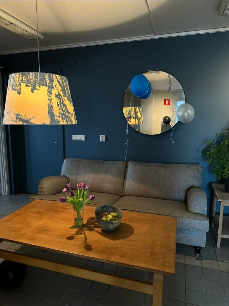 Loungen med soffa, soffbord och spegel mot den blå väggen